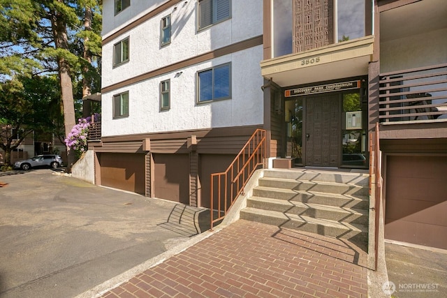 3505 W Government Way Unit 203, Seattle, WA 98199 - view of exterior entry featuring a garage, stucco siding, and driveway