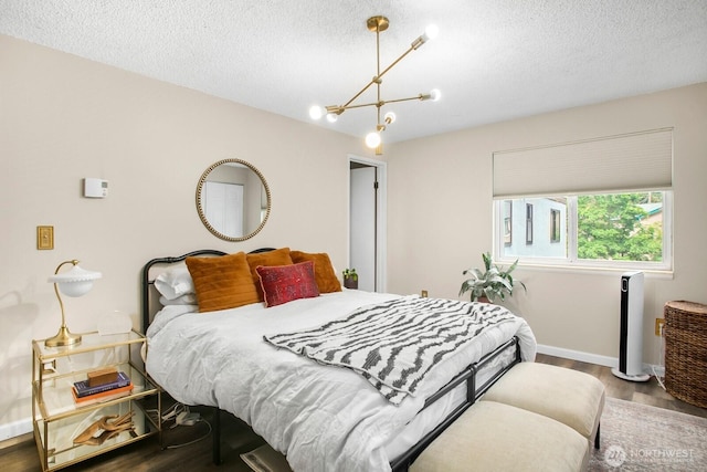 3505 W Government Way Unit 203, Seattle, WA 98199 - bedroom with a chandelier, wood finished floors, a textured ceiling, and baseboards