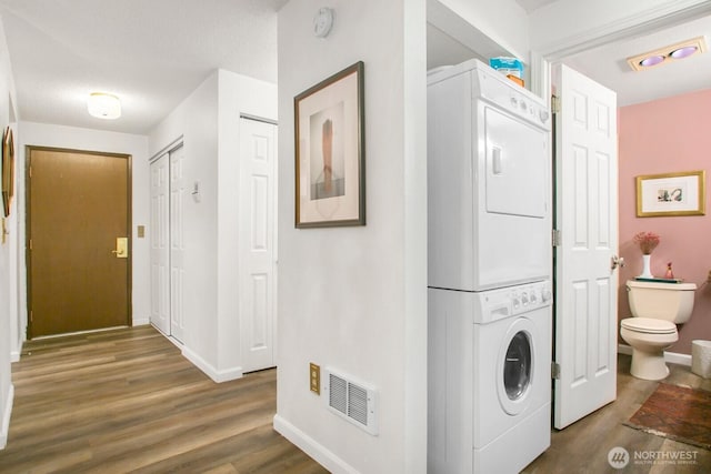 3505 W Government Way Unit 203, Seattle, WA 98199 - laundry area featuring stacked washer and clothes dryer, wood finished floors, and baseboards
