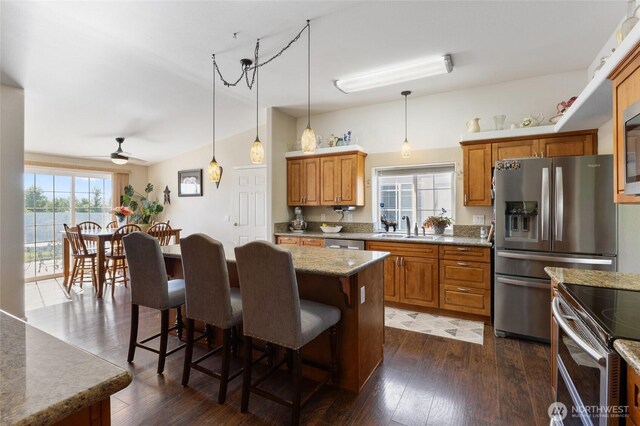 1183 E.9 Rd NE, Moses Lake, WA 98837 - kitchen with a sink, a breakfast bar, lofted ceiling, brown cabinetry, and dark wood-type flooring