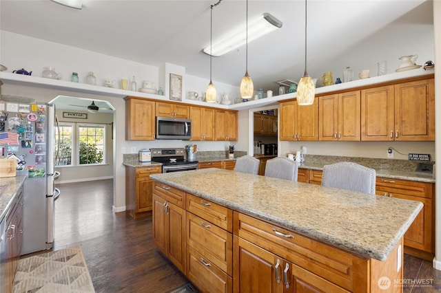 1183 E.9 Rd NE, Moses Lake, WA 98837 - kitchen featuring appliances with stainless steel finishes, a kitchen island, dark wood-style floors, and light stone countertops