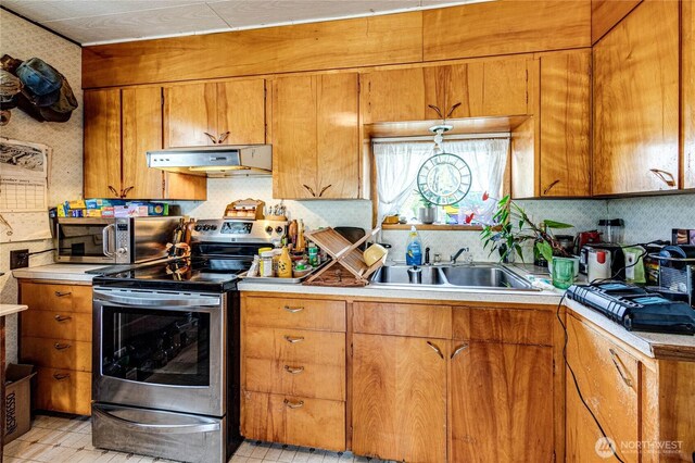 16672 Frontier St, Clallam Bay, WA 98326 - kitchen featuring under cabinet range hood, appliances with stainless steel finishes, brown cabinets, and light countertops