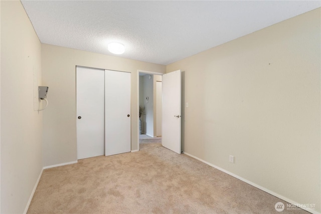 24727 12th Ave S, Des Moines, WA 98198 - unfurnished bedroom featuring light carpet, a closet, a textured ceiling, and baseboards