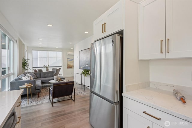 13713 35th Ave NE Unit A, Seattle, WA 98125 - kitchen featuring freestanding refrigerator, white cabinetry, light stone countertops, light wood-type flooring, and recessed lighting