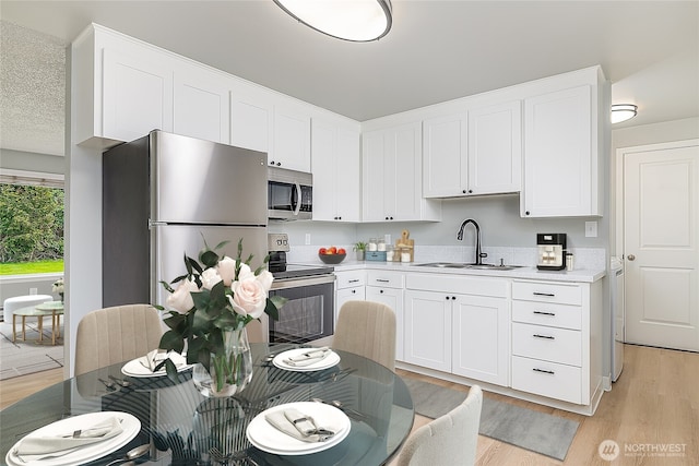12672 179th Ave SE, Monroe, WA 98272 - kitchen with stainless steel appliances, a sink, light wood finished floors, and white cabinets