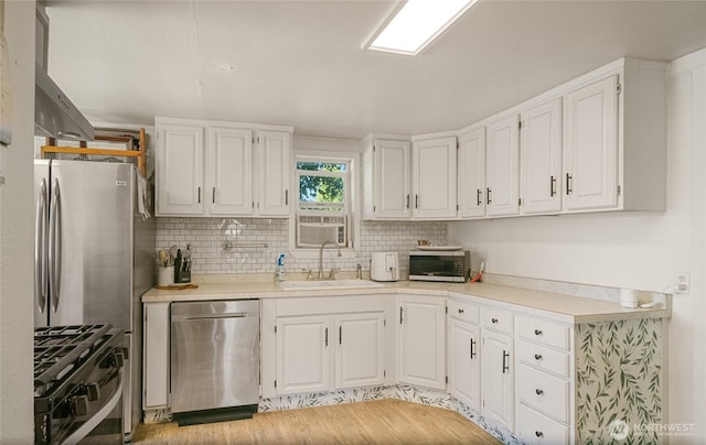 632 Dayton St, Omak, WA 98841 - kitchen featuring stainless steel appliances, a sink, white cabinetry, tasteful backsplash, and light countertops