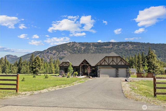 1550 Old Cedars Rd, Cle Elum, WA 98922 - tudor home featuring a mountain view, asphalt driveway, a garage, and a wooded view