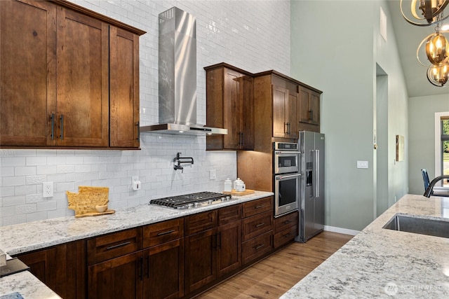 1550 Old Cedars Rd, Cle Elum, WA 98922 - kitchen featuring wall chimney exhaust hood, stainless steel appliances, a towering ceiling, a sink, and wood finished floors