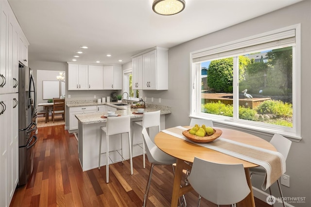 10808 158th Ct NE, Redmond, WA 98052 - kitchen with freestanding refrigerator, a peninsula, white cabinetry, a sink, and healthy amount of natural light