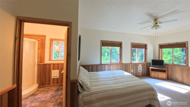 321 N Lake Surf Dr, Lilliwaup, WA 98555 - bedroom with multiple windows, a wainscoted wall, wood walls, stone finish floors, and a ceiling fan