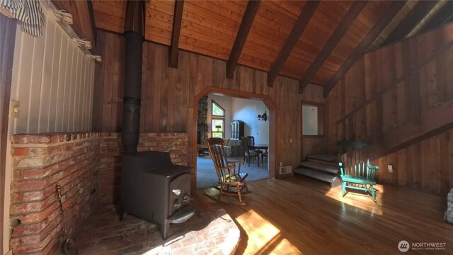 321 N Lake Surf Dr, Lilliwaup, WA 98555 - unfurnished living room with wooden walls, wood finished floors, a wood stove, arched walkways, and stairs