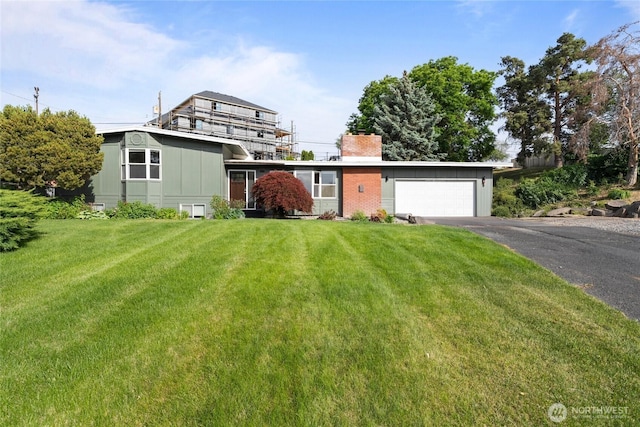 1147 Ashley Way, Moses Lake, WA 98837 - view of front of house featuring driveway, an attached garage, a front yard, a chimney, and board and batten siding