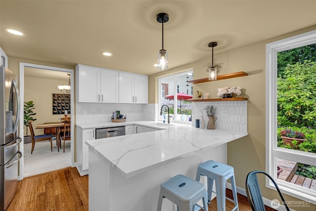 17620 NE 29th St, Redmond, WA 98052 - kitchen featuring stainless steel appliances, a sink, a peninsula, light stone counters, and white cabinets