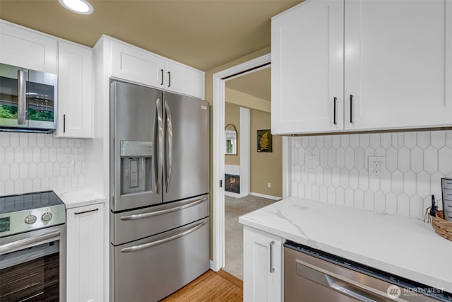 17620 NE 29th St, Redmond, WA 98052 - kitchen featuring appliances with stainless steel finishes, white cabinets, backsplash, and light stone countertops