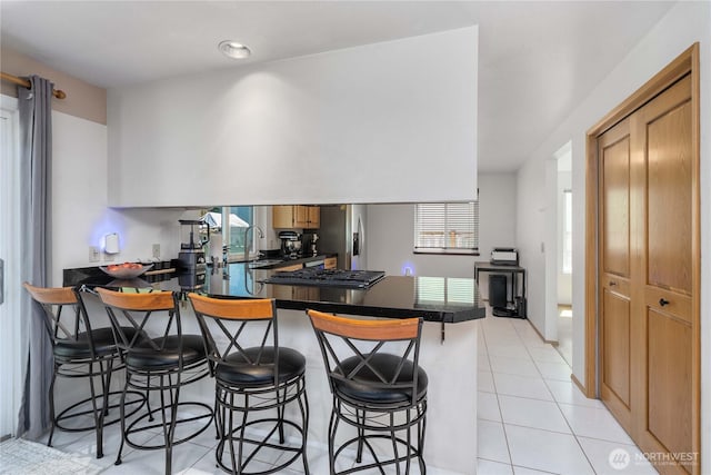 27742 214th Ave SE, Maple Valley, WA 98038 - kitchen featuring a peninsula, dark countertops, healthy amount of natural light, and light tile patterned floors