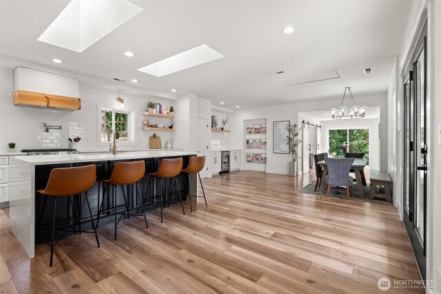 9814 36th St E, Edgewood, WA 98371 - bar area with a sink, tasteful backsplash, a skylight, light wood-style floors, and custom exhaust hood