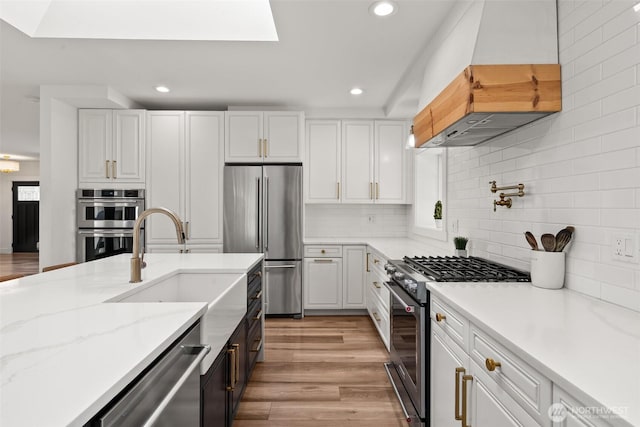 9814 36th St E, Edgewood, WA 98371 - kitchen featuring appliances with stainless steel finishes, premium range hood, a sink, recessed lighting, and white cabinetry