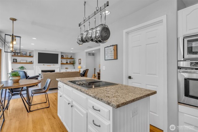 25161 13th Ave S, Des Moines, WA 98198 - kitchen featuring stainless steel appliances, a kitchen island, a fireplace, light wood-type flooring, and white cabinets