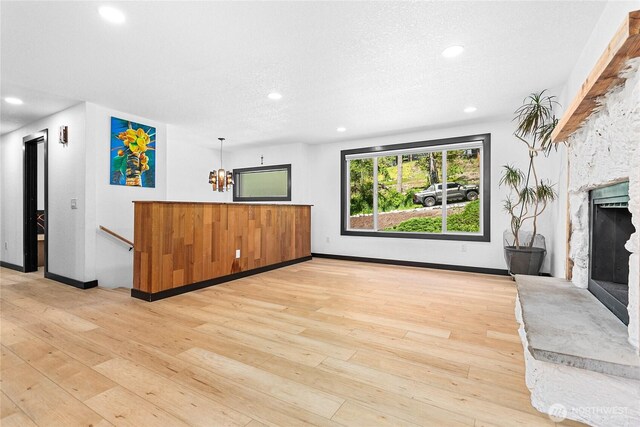 1668 Sapphire Trl, Bellingham, WA 98226 - unfurnished living room featuring a stone fireplace, light wood-style flooring, recessed lighting, baseboards, and a textured ceiling