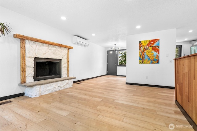 1668 Sapphire Trl, Bellingham, WA 98226 - unfurnished living room featuring an AC wall unit, light wood-style flooring, recessed lighting, a stone fireplace, and baseboards