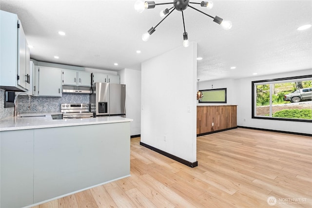 1668 Sapphire Trl, Bellingham, WA 98226 - kitchen with a sink, stainless steel appliances, under cabinet range hood, light countertops, and light wood-style floors