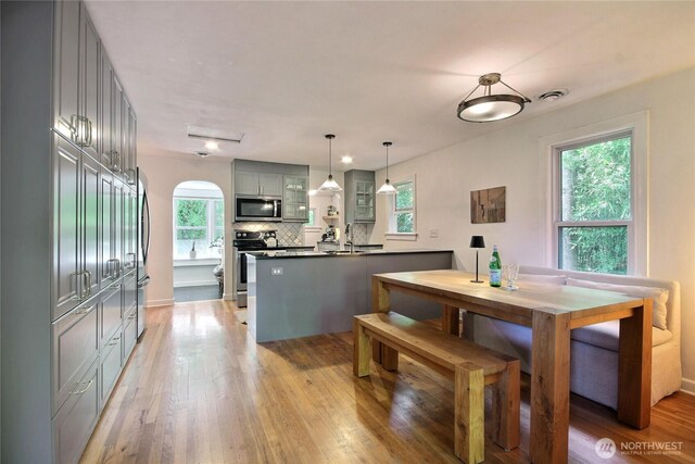 719 N 92nd St, Seattle, WA 98103 - dining room featuring healthy amount of natural light, light wood-style flooring, arched walkways, and baseboards