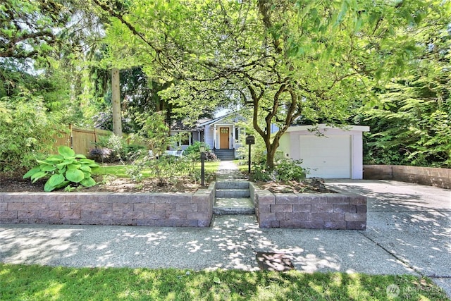 719 N 92nd St, Seattle, WA 98103 - view of property hidden behind natural elements with concrete driveway and a garage