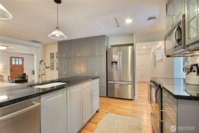 719 N 92nd St, Seattle, WA 98103 - kitchen featuring appliances with stainless steel finishes, a sink, dark countertops, light wood-style floors, and gray cabinetry