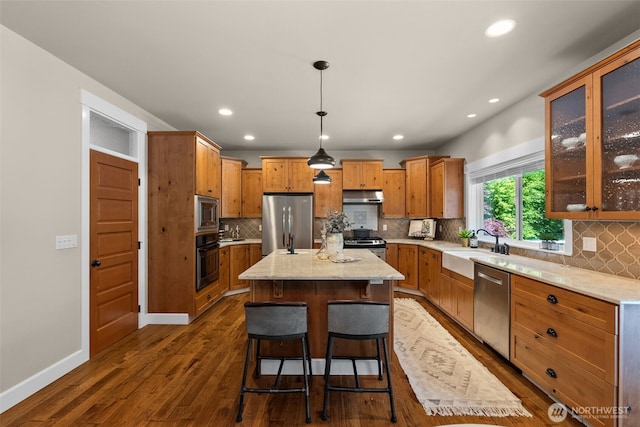 1808 153rd Street Ct NW, Gig Harbor, WA 98332 - kitchen with appliances with stainless steel finishes, under cabinet range hood, a center island, a sink, and decorative backsplash