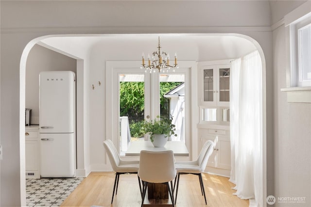 707 Ryan Ave, Sumner, WA 98390 - dining room with a chandelier, arched walkways, and light wood-style flooring