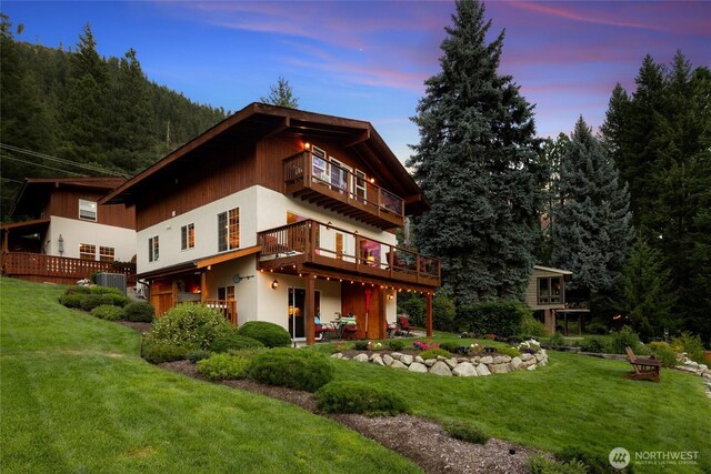 8775 Icicle Rd, Leavenworth, WA 98826 - back of house at dusk featuring a yard, central air condition unit, a wooden deck, and a patio area