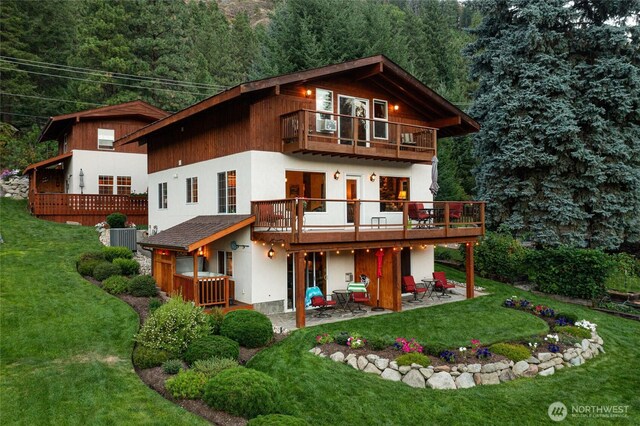 8775 Icicle Rd, Leavenworth, WA 98826 - back of property featuring a balcony, a patio, a yard, and a forest view