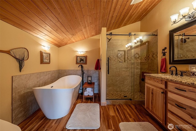 8775 Icicle Rd, Leavenworth, WA 98826 - bathroom with lofted ceiling, a freestanding bath, vanity, a shower stall, and tile walls