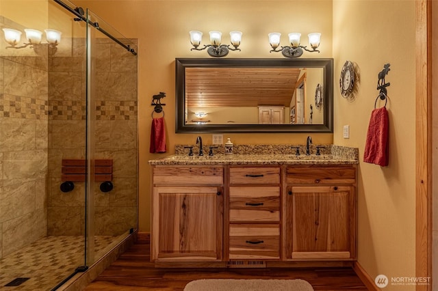 8775 Icicle Rd, Leavenworth, WA 98826 - bathroom featuring wood finished floors, double vanity, and a tile shower