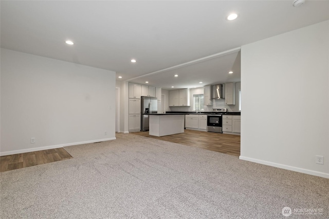 17101 Snowbell Ct SE, Yelm, WA 98597 - unfurnished living room featuring light colored carpet, baseboards, recessed lighting, light wood finished floors, and a sink