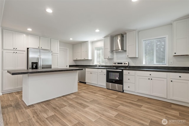 17101 Snowbell Ct SE, Yelm, WA 98597 - kitchen featuring wall chimney range hood, appliances with stainless steel finishes, white cabinetry, a sink, and light wood-type flooring