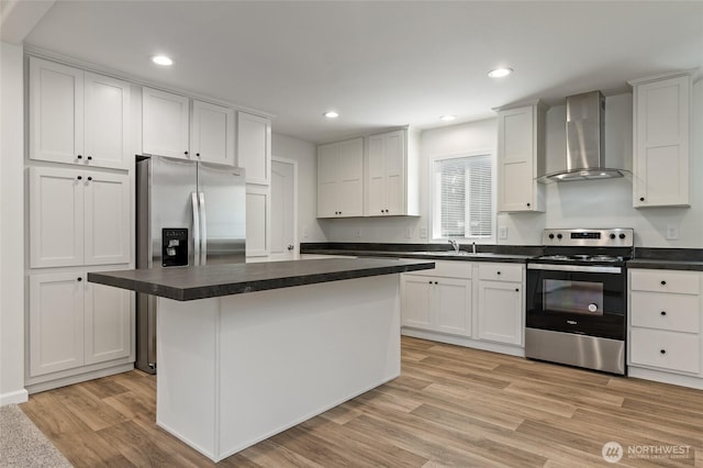 17101 Snowbell Ct SE, Yelm, WA 98597 - kitchen with wall chimney range hood, stainless steel appliances, dark countertops, light wood-style flooring, and white cabinets