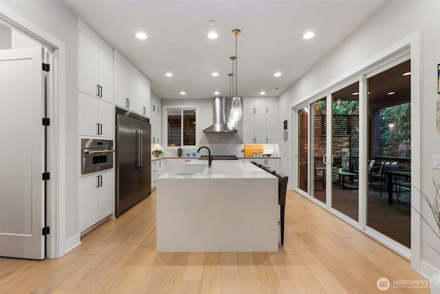 1201 222nd Ct SE, Sammamish, WA 98075 - kitchen with appliances with stainless steel finishes, wall chimney exhaust hood, light wood-style flooring, white cabinetry, and light countertops