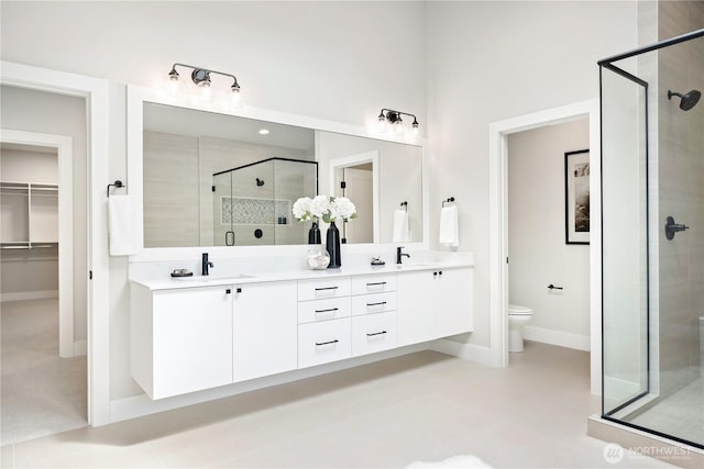 1201 222nd Ct SE, Sammamish, WA 98075 - full bathroom featuring a shower stall, double vanity, toilet, a walk in closet, and baseboards