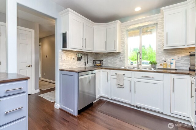 14918 Champion Estates Dr SE, Yelm, WA 98597 - kitchen featuring stainless steel dishwasher, dark wood-style flooring, decorative backsplash, white cabinets, and dark countertops