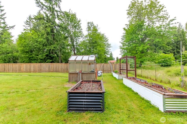 14918 Champion Estates Dr SE, Yelm, WA 98597 - fenced backyard featuring a vegetable garden, a greenhouse, and an outdoor structure