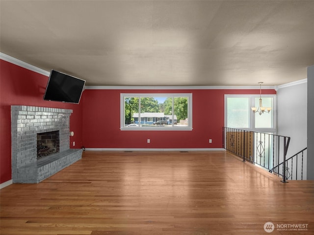 11822 10th Ave S, Seattle, WA 98168 - unfurnished living room featuring a chandelier, ornamental molding, wood finished floors, healthy amount of natural light, and a brick fireplace