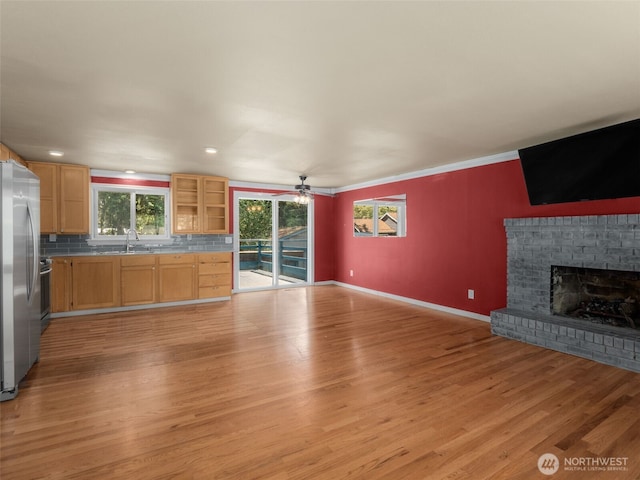 11822 10th Ave S, Seattle, WA 98168 - unfurnished living room with light wood-style floors, plenty of natural light, a ceiling fan, a fireplace, and ornamental molding