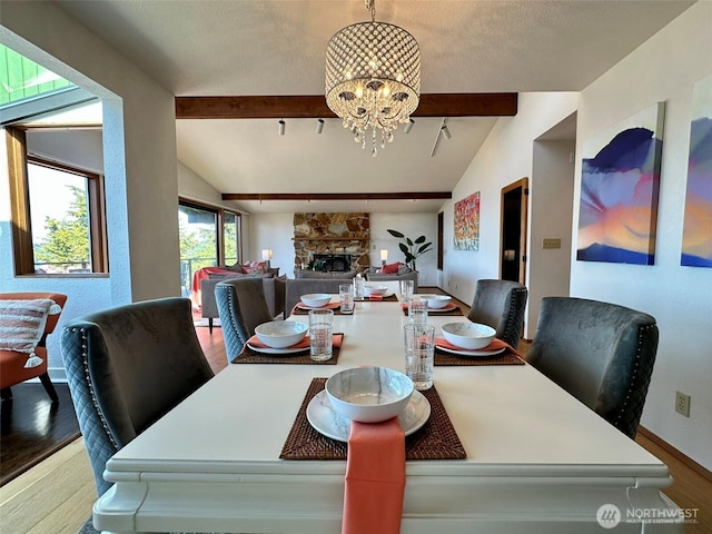 714 SW 296th St, Federal Way, WA 98023 - dining area with wood finished floors, a chandelier, a stone fireplace, baseboards, and rail lighting