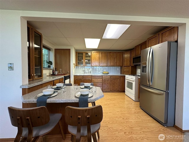 714 SW 296th St, Federal Way, WA 98023 - kitchen with stainless steel appliances, a peninsula, glass insert cabinets, light wood-type flooring, and a paneled ceiling