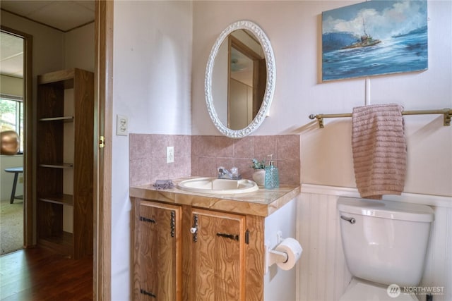1851 Washington Dr, Point Roberts, WA 98281 - bathroom featuring toilet, vanity, a wainscoted wall, wood finished floors, and backsplash