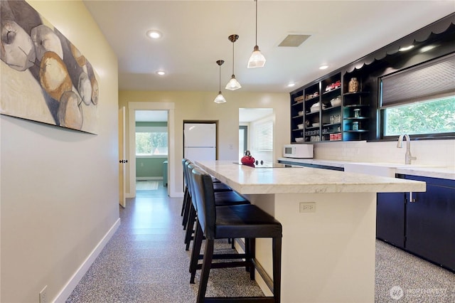 1250 Bryant, Walla Walla, WA 99362 - kitchen with baseboards, white microwave, dark aggregate flooring, light countertops, and a kitchen island