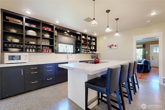 1250 Bryant, Walla Walla, WA 99362 - kitchen featuring white microwave, open shelves, backsplash, light countertops, and a center island