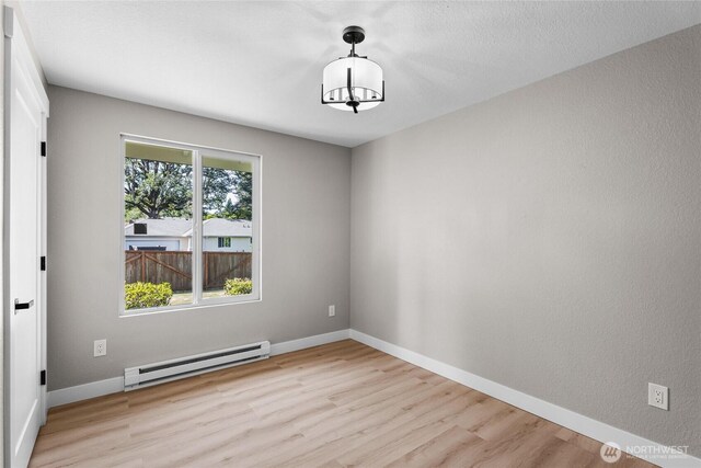 3801 Ruddell Rd SE, Lacey, WA 98503 - empty room with a baseboard radiator, light wood-style flooring, baseboards, and a chandelier