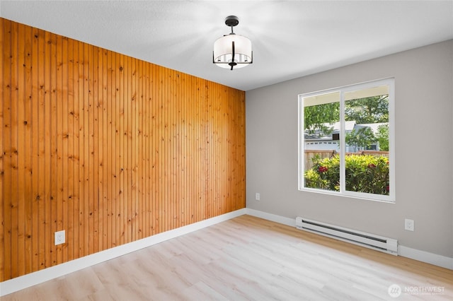 3801 Ruddell Rd SE, Lacey, WA 98503 - unfurnished room featuring a baseboard radiator, wood finished floors, wooden walls, and baseboards
